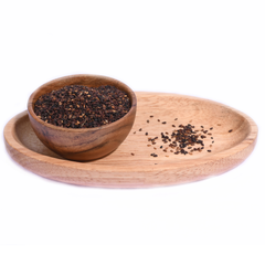 A wooden bowl filled with black sesame seeds, showing their smooth