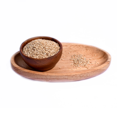 Close-up of small, oval-shaped white sesame seeds, scattered across a smooth surface. The seeds are off-white in color, slightly shiny, and have a delicate texture