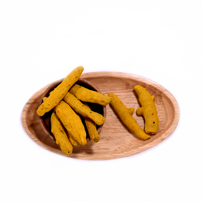 A pile of turmeric sticks, bright yellow and slightly curved, placed on a wooden board