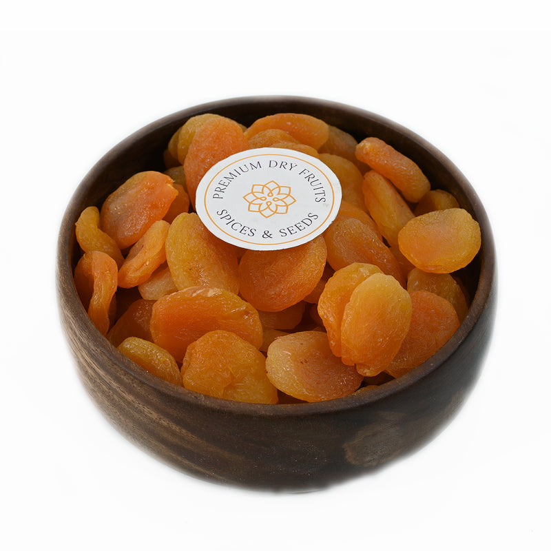 Five dried apricots displayed on a black background, showcasing their vibrant orange color and slightly wrinkled textures. House of Rasda offers a wide variety of high-quality apricot products, including dried Turkish apricots